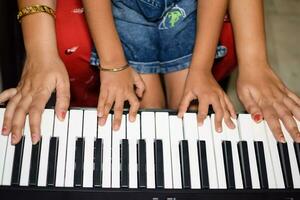 Aziatisch jongen spelen de synthesizer of piano. schattig weinig kind aan het leren hoe naar Speel piano. kind handen Aan de toetsenbord binnen. foto