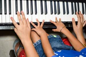 Aziatisch jongen spelen de synthesizer of piano. schattig weinig kind aan het leren hoe naar Speel piano. kind handen Aan de toetsenbord binnen. foto