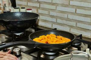 helften van vers abrikozen zijn gebakken in karamel siroop in frituren pan Aan gas- fornuis foto