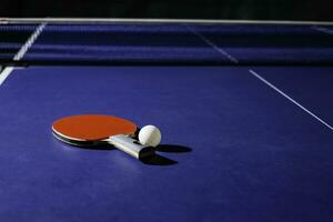 tafel tennis racket Aan de blauw ping pong tafel foto