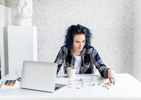 ontwerper aan het werk met kleurenpaletten en laptop in haar studio foto