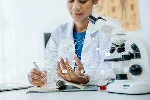 jong wetenschappers dirigeren Onderzoek onderzoeken in een medisch laboratorium, een onderzoeker in de voorgrond is gebruik makend van een microscoop in laboratorium voor geneesmiddel. foto