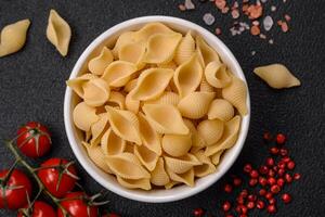 rauw Italiaans pasta conchiglie van durum tarwe met groenten, zout en specerijen foto