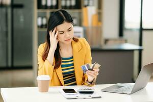 Aziatisch bedrijf vrouw is gestrest, verveeld, en over analyseren van werken Aan een tablet Bij de kantoor. foto