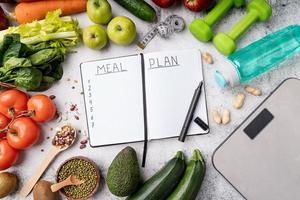 notitieblok met woorden maaltijdplan met gezonde voeding en sportuitrusting foto