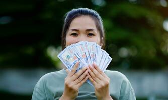 dollar in de handen van een Aziatisch vrouw besparingen, investeringen, salaris, inkomen, contant geld stromen, geluk en financieel succes en investeringen. foto