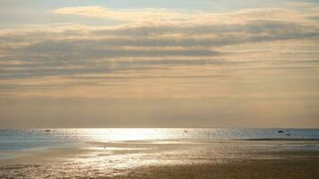 zonsondergang, verlichte zee. zanderig strand in de voorgrond. licht golven. Baltisch zee foto