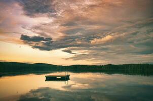 zwemmen eiland in Zweden Aan een meer Bij zonsondergang. wolken weerspiegeld in de water. foto