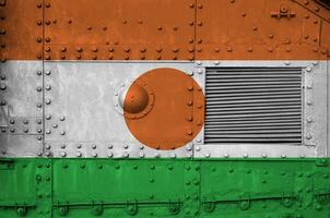 Niger vlag afgebeeld Aan kant een deel van leger gepantserd tank detailopname. leger krachten conceptuele achtergrond foto