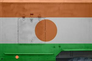 Niger vlag afgebeeld Aan kant een deel van leger gepantserd vrachtauto detailopname. leger krachten conceptuele achtergrond foto