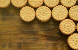 een ronde belegd broodje koekje met kokosnoot vulling leugens in groot hoeveelheden Aan een bruin houten oppervlak. foto van eetbaar behandelt Aan een houten achtergrond met kopiëren ruimte