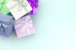 stapel van een klein gekleurde geschenk dozen met linten leugens Aan een paars achtergrond. minimalisme vlak leggen top visie foto