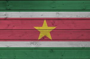Suriname vlag afgebeeld in helder verf kleuren Aan oud houten muur. getextureerde banier Aan ruw achtergrond foto