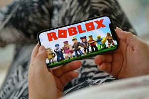 roblox mobiel iOS spel Aan iphone 15 smartphone scherm in vrouw handen gedurende mobiel gameplay foto