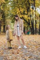 moeder en haar dochter hebben plezier en wandelen in het herfstpark. foto