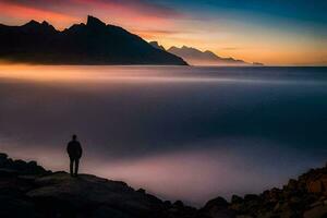 een Mens staand Aan een rots met uitzicht de oceaan Bij zonsondergang. ai-gegenereerd foto
