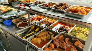 padang voedsel kraampjes delen een verscheidenheid van buffet menu's met groenten, kip kerrie saus, rundvlees, eieren, tofu, tempeh. foto