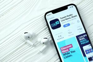 Charkov, Oekraïne - maart 5, 2021 inschakelen muziek- icoon en toepassing van app op te slaan Aan iphone 12 pro Scherm scherm met airpods pro Aan wit tafel foto