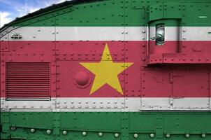 Suriname vlag afgebeeld Aan kant een deel van leger gepantserd tank detailopname. leger krachten conceptuele achtergrond foto