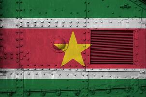 Suriname vlag afgebeeld Aan kant een deel van leger gepantserd tank detailopname. leger krachten conceptuele achtergrond foto