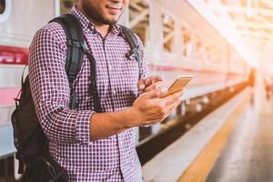 jonge man die op het treinstation staat en smartphone gebruikt