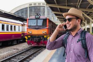 jonge man die op het treinstation staat en smartphone gebruikt