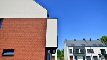 buitenwijk buurt met condominium complex. buitenwijk Oppervlakte met modern meetkundig familie huizen. rij van familie huizen tegen blauw lucht. foto