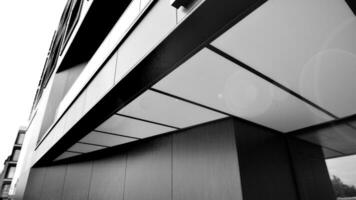 een visie Bij een Rechtdoor facade van een modern gebouw met een donker grijs facade. donker grijs metalen paneel gevel. modern bouwkundig details. zwart en wit. foto