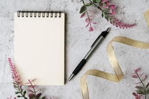 notitieboekje, pen en bloem worden op een witte achtergrond geplaatst foto