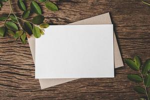 een blanco kaart wordt op envelop en blad met houten achtergrond geplaatst