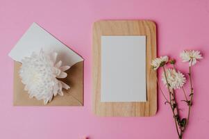 bruine envelop, bloem en blanco kaart op houten plaat met roze foto