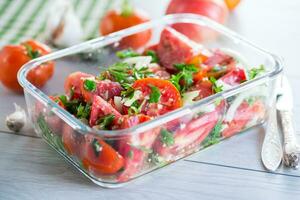 pittig tussendoortje tomaten met knoflook, kruiden, kruiderijen en uien in een glas kom . foto