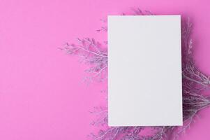 blanco papier met bloemen op een roze achtergrond foto