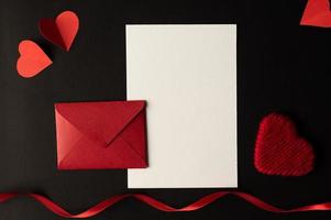 wit papier en rood hartpapier geplakt op een zwarte achtergrond. foto