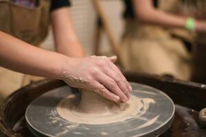 pottenbakker meisje werken Aan pottenbakker wiel, maken keramisch pot uit van klei in pottenbakkerij werkplaats foto
