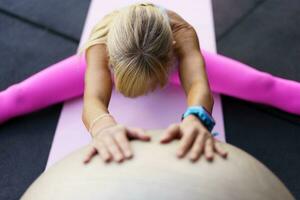 onherkenbaar vrouw aan het doen uitrekken oefening met geschiktheid bal in Sportschool Aan mat foto