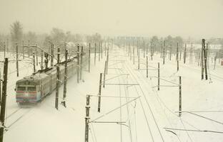 een lang trein van passagier auto's is in beweging langs de spoorweg spoor. spoorweg landschap in winter na sneeuwval foto