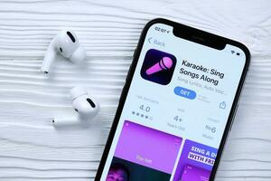 Charkov, Oekraïne - maart 5, 2021 karaoke icoon en toepassing van app op te slaan Aan iphone 12 pro Scherm scherm met airpods pro Aan wit tafel foto