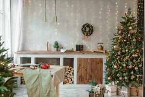 huis nieuw jaar interieur. Kerstmis boom met geschenken, versierd met slingers in de keuken. knus atmosfeer van een huis vakantie, zolder ontwerp van de kamer, Scandinavisch stijl. foto