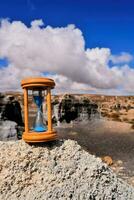 een zandloper zittend Aan top van een rots in de woestijn foto