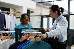 Afrikaanse Amerikaans klant op zoek Bij gewoontjes dragen, boodschappen doen voor elegant handelswaar in modern boetiek. shopaholic vrouw willen nieuw garderobe, buying modieus kleren in kleding op te slaan foto