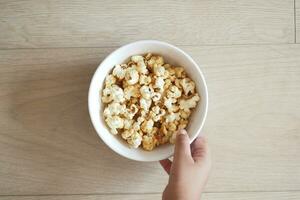 top visie van kind hand- Holding een kom van popcorn foto