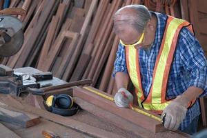 oude aziatische man timmerman die in een houtbewerkingsfabriek werkt. foto