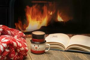 winter instelling met deken heet koffie en een boek door een brand foto