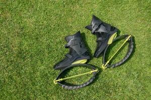 kangoo springt laarzen Aan groen gras. zwart kangoo sportschoenen met geel grasmat lappen. modern schoenen voor fitheid, aerobics. foto