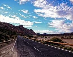 een weg in de woestijn met bergen in de achtergrond foto