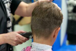 haar- snijdend voor een kind gebruik makend van een haar- tondeuse in een schoonheid salon foto