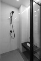 zwart douche hoofd Aan houder tegen betegeld muur Aan achtergrond. concept van wit badkamer in modern flat foto