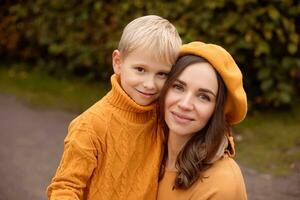 portret van een mooi jong moeder en 6 jaar oud zoon in oranje herfst kleren. foto