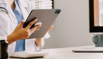 medisch dokter of arts overleg plegen patiënten Gezondheid online gebruik makend van internet mobiel digitaal tablet in kliniek of ziekenhuis kantoor voor professioneel noodgeval gezondheidszorg bijstand onderhoud concept foto